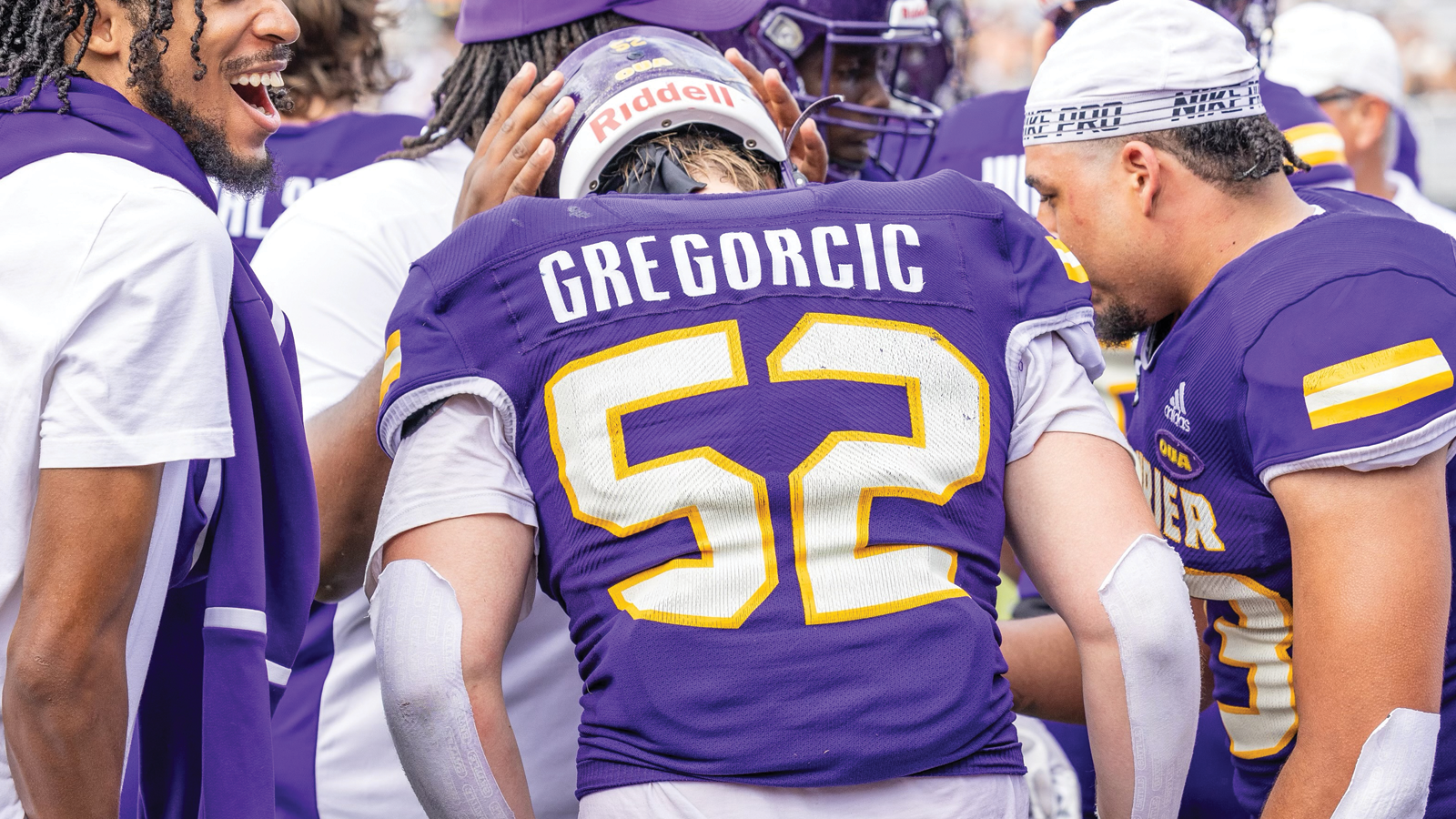Action photo of Laurier football player Ethan Gregorcic facing away from the camera within a team huddle