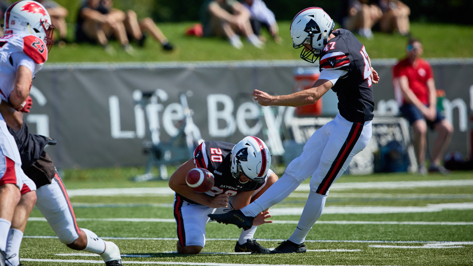 Action photo of Carleton football player having just kicked the ball for a field goal attempt, as the ball takes off through the air and the kicker follows through on the kick