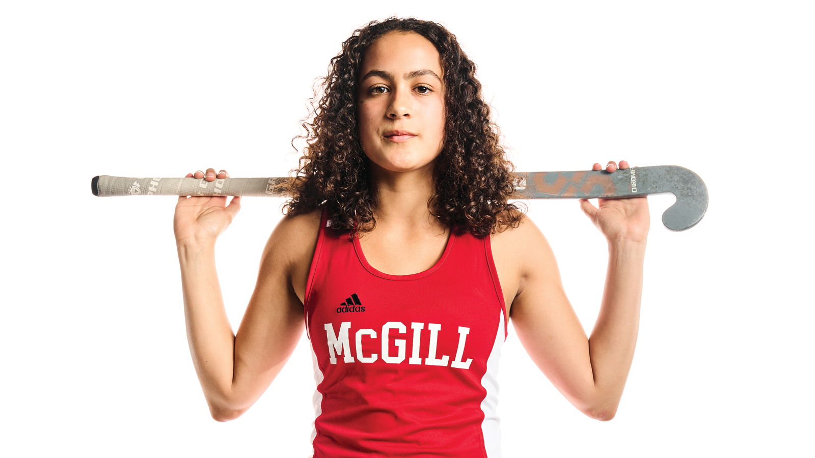 Posed photo of McGill field hockey player Ada Collins with her stick positioned perpendicular to her body as she holds it over her shoulders and behind her head