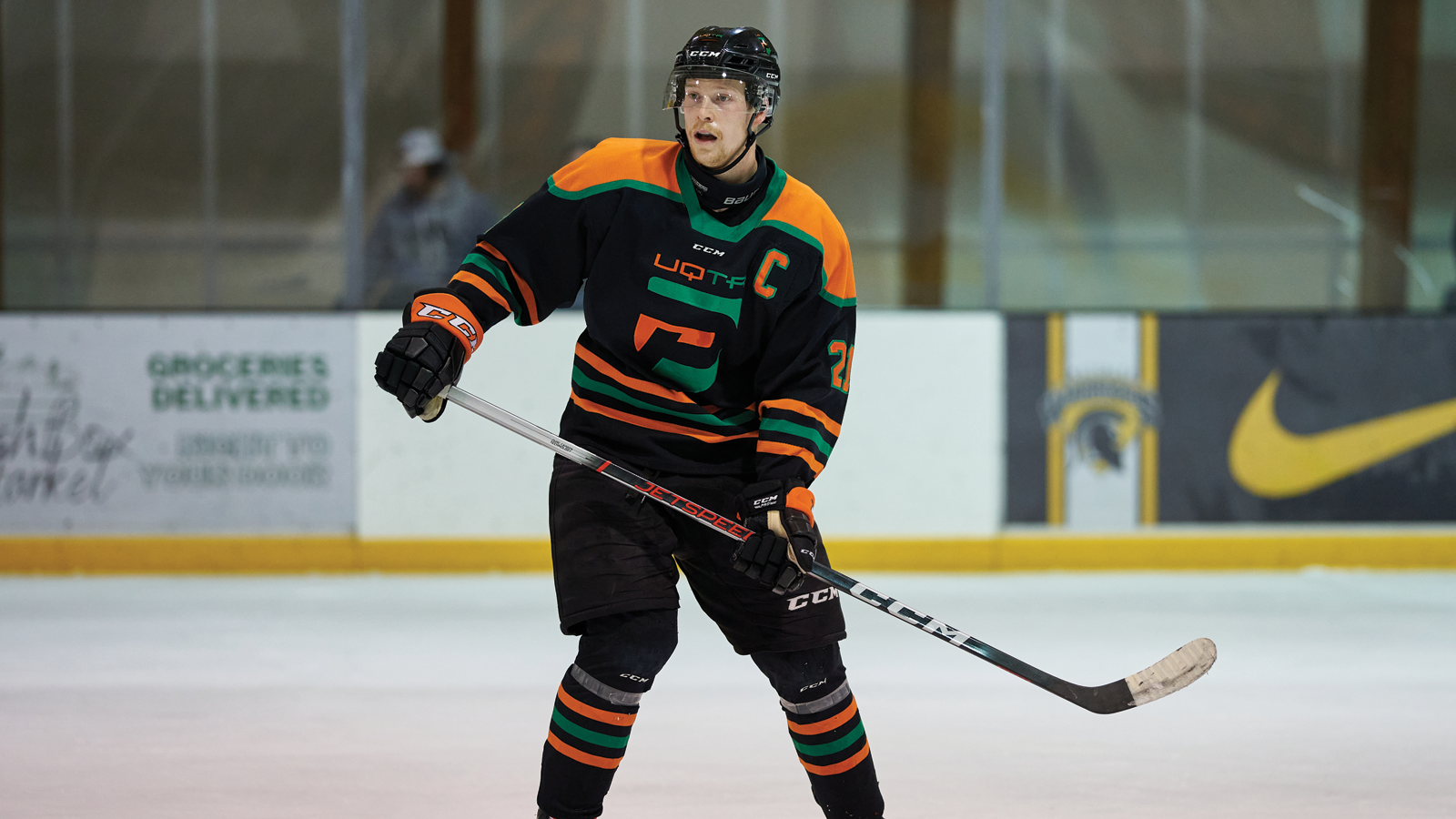 UQTR hockey player David Noel skating on the ice with his stick parallel to the ice as he looks out toward the play during a game