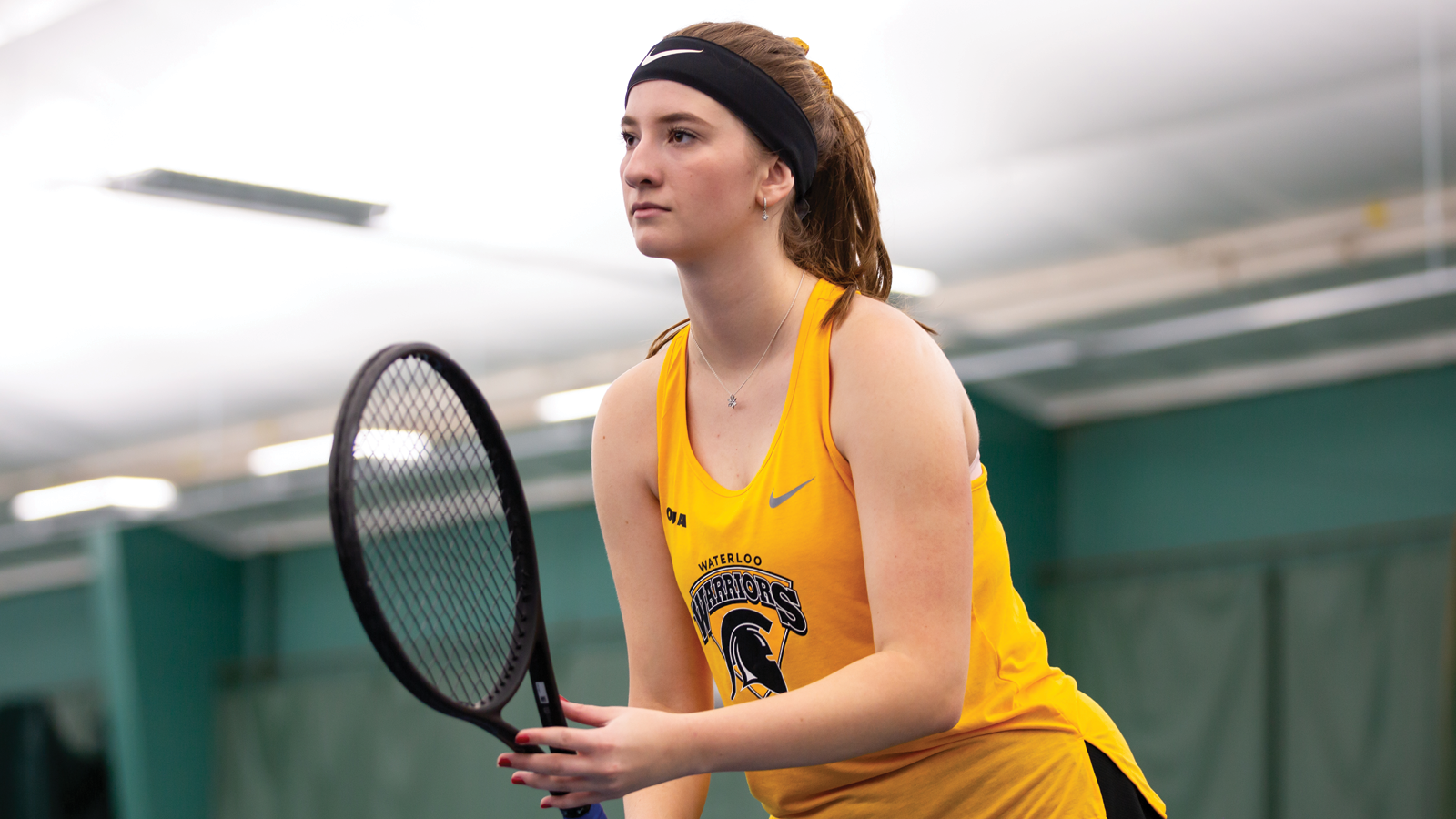 Action photo of Waterloo women's tennis player holding her racquet in the ready position prior to a point
