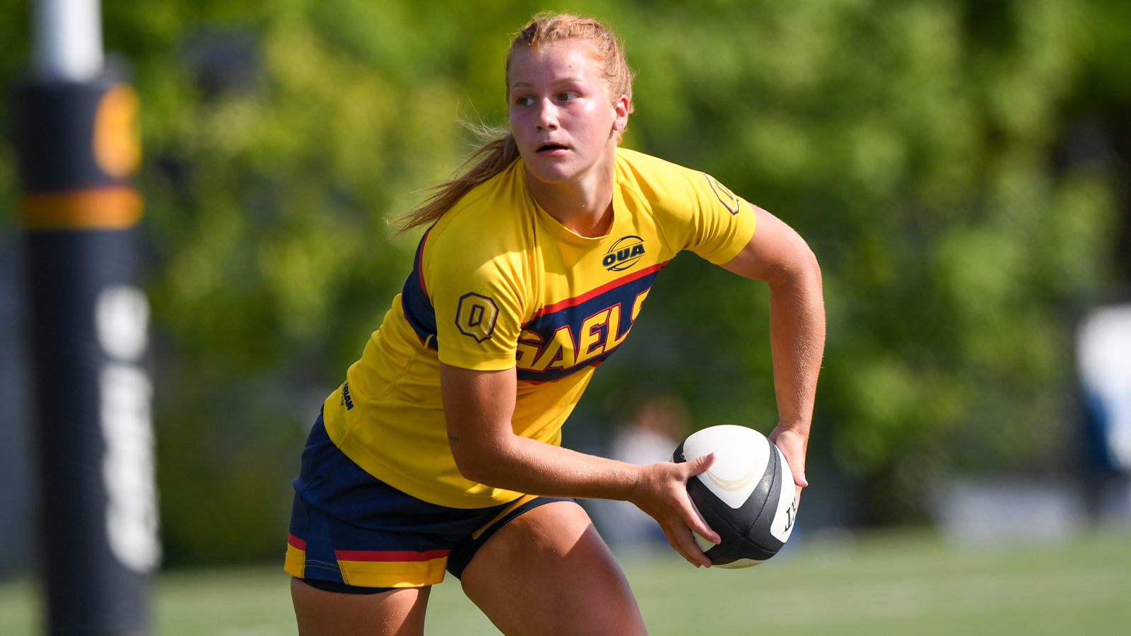 Queen's women's rugby player on the field about to pass the ball