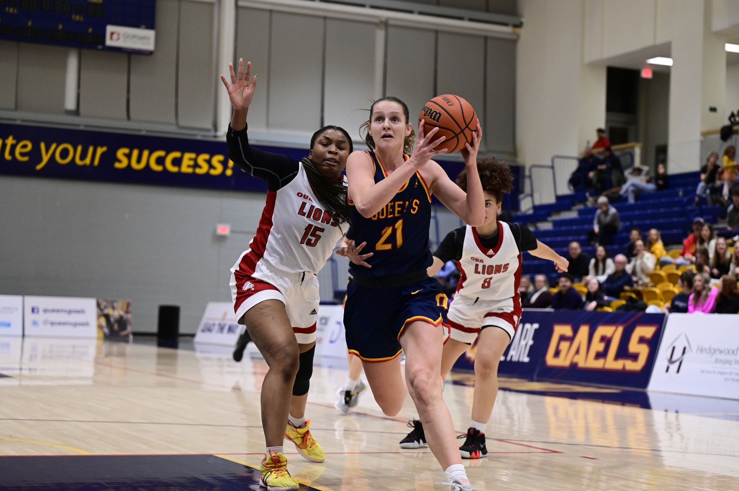 Image of Women's Basketball Athlete of the Week Julia Chadwick holding a ball no the right side with both hands as she is stepping forward and away from the defender on her left. 