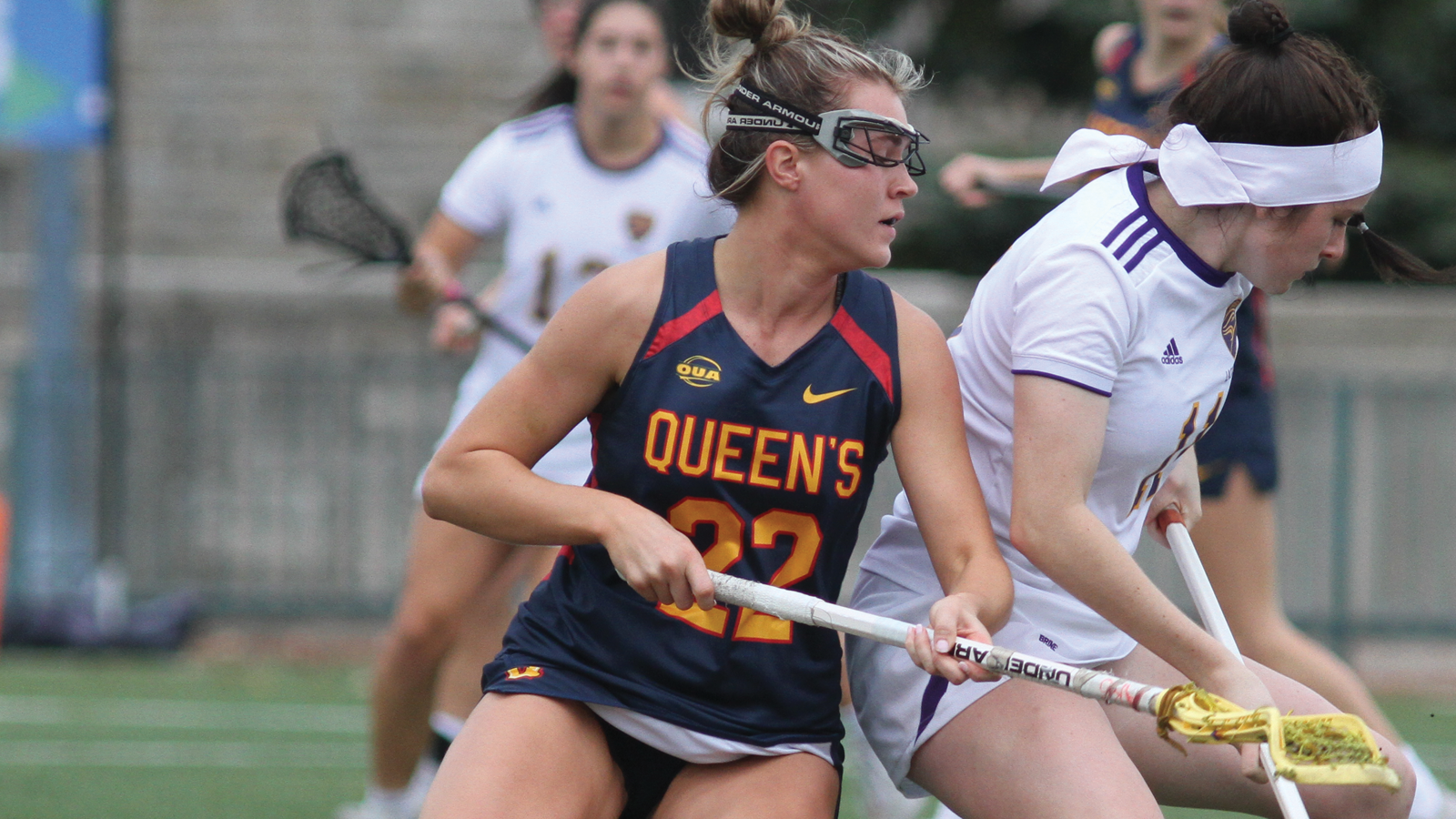 Queen's women's lacrosse player Abby Lee competing for the ball with an opposing player during a game
