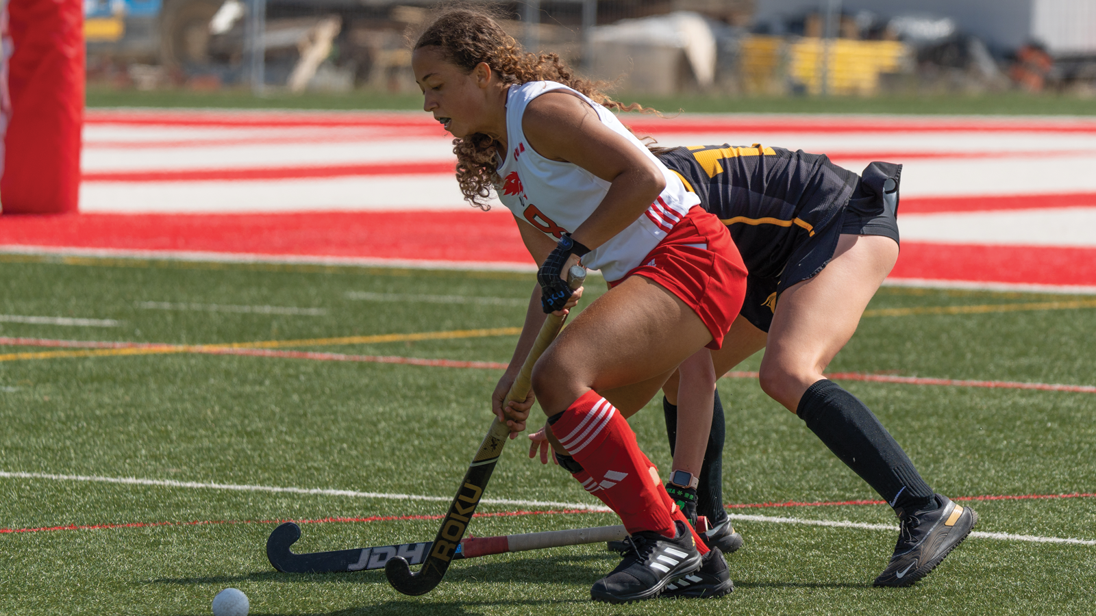 Action photo of York field hockey player Juliet Redelaar running with the ball on her stick while fending off a Waterloo defender