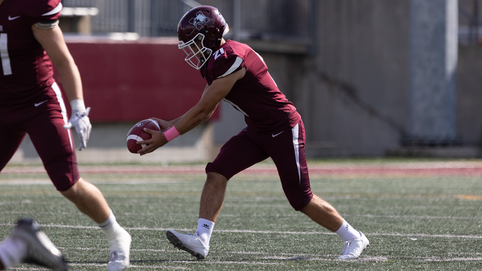 Action photo of McMaster kicked Luca Pante holding the ball about to punt it during a game