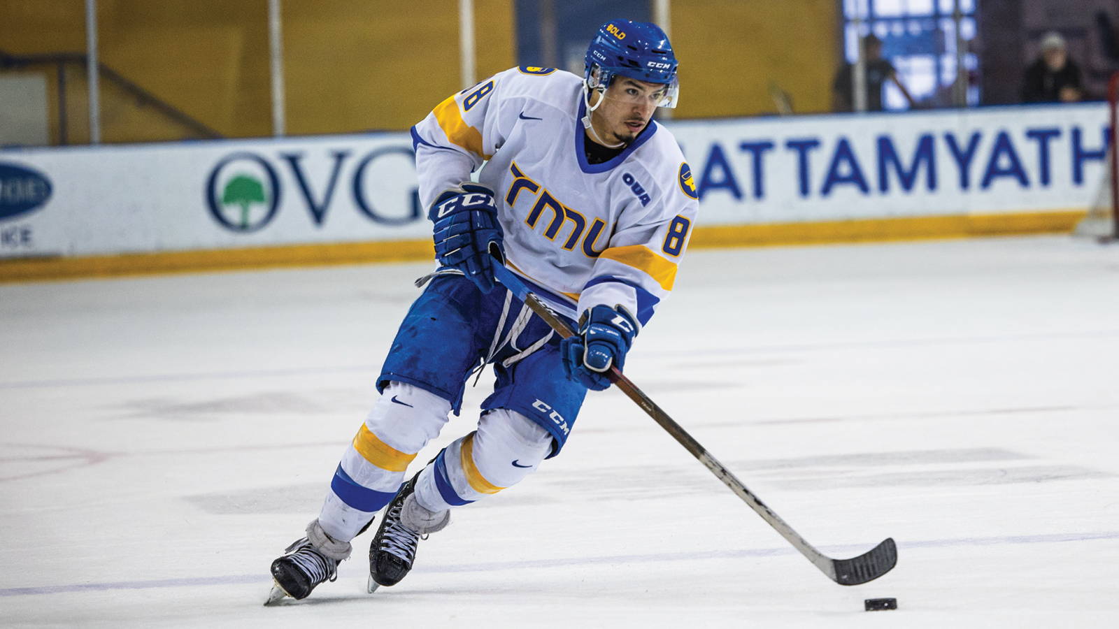 Action phot of TMU men's hockey player Kyle Bollers skating with the puck at his home arena