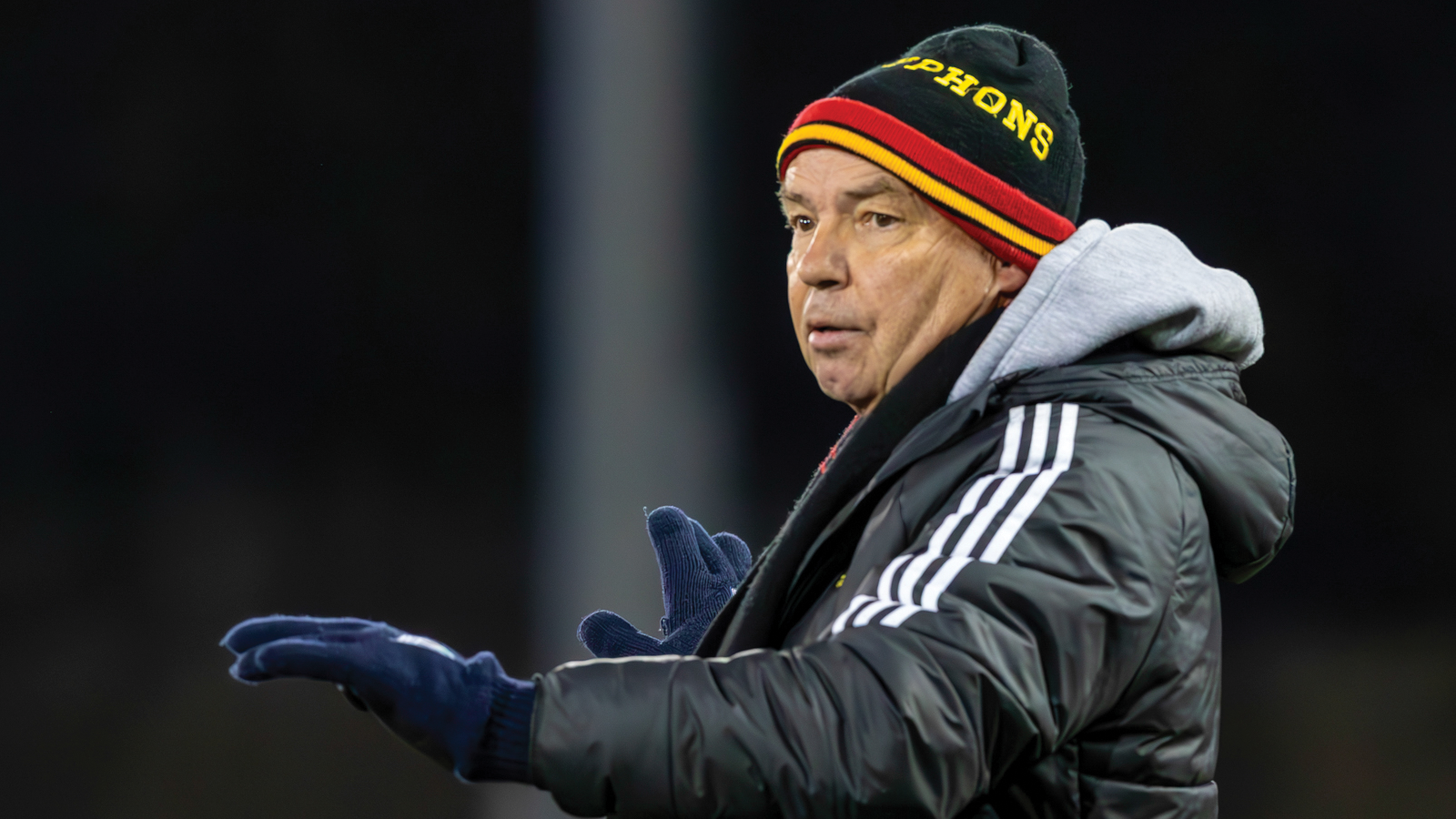 Guelph men's soccer coach Keith mason wearing a Gryphons toque and winter jacket while looking outward toward the field