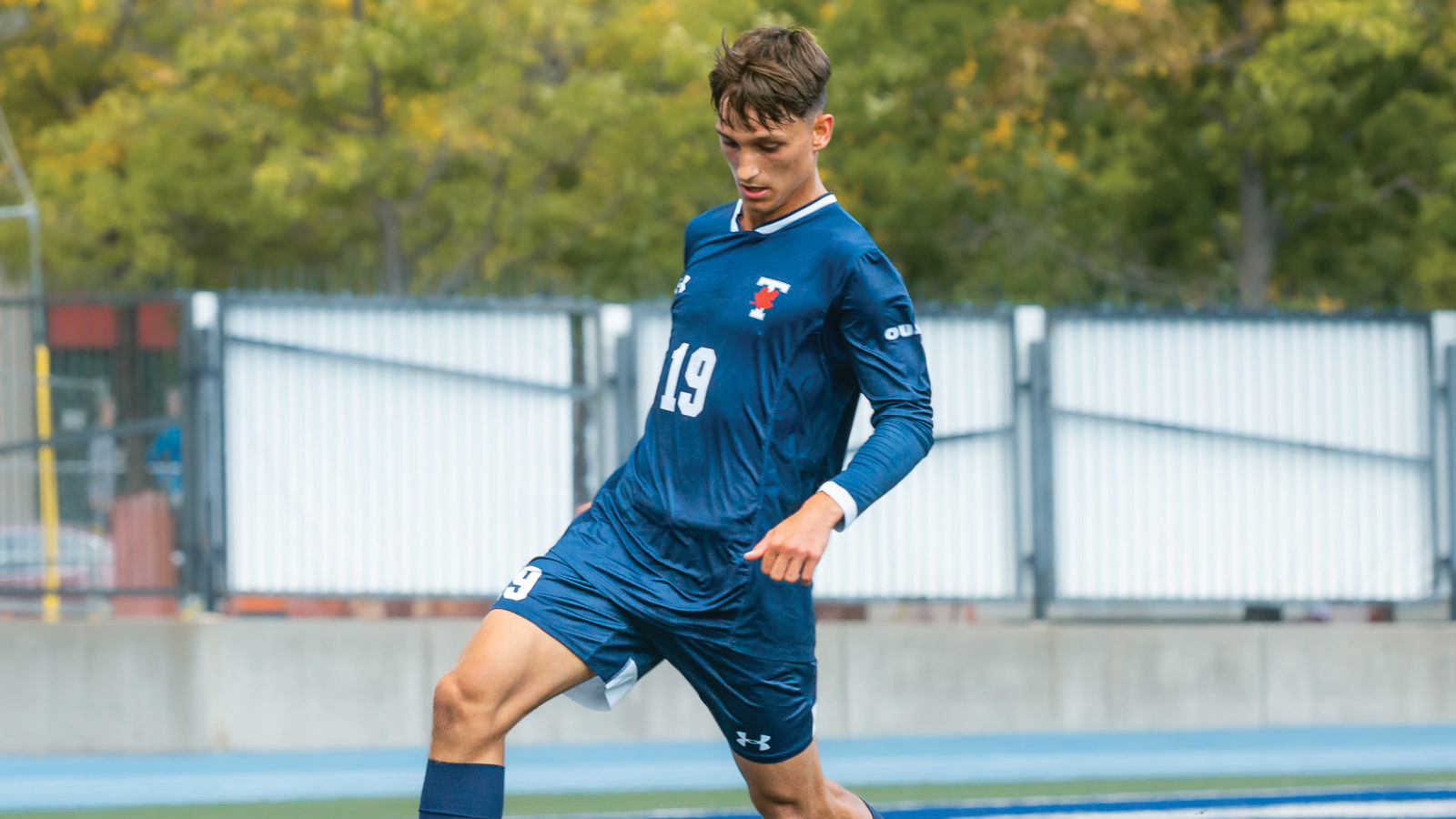 Toronto men's soccer player Michael Maslanka looking down toward the field with the ball at his feet during a game