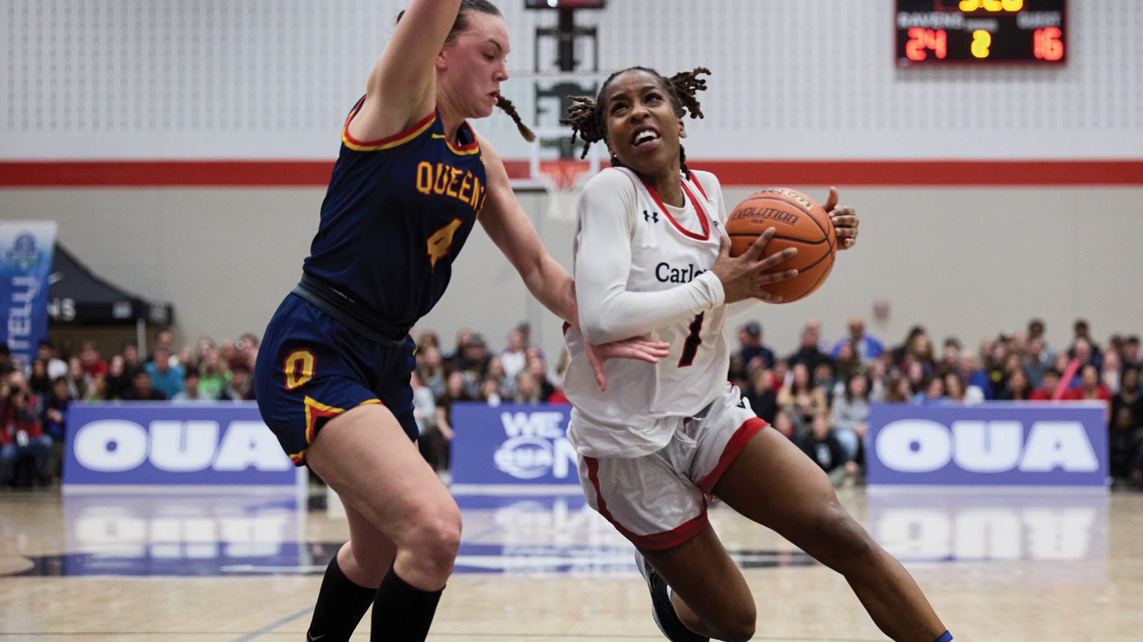 Carleton women's basketball player driving the ball through the lane against a Queen's defender during the OUA championship game