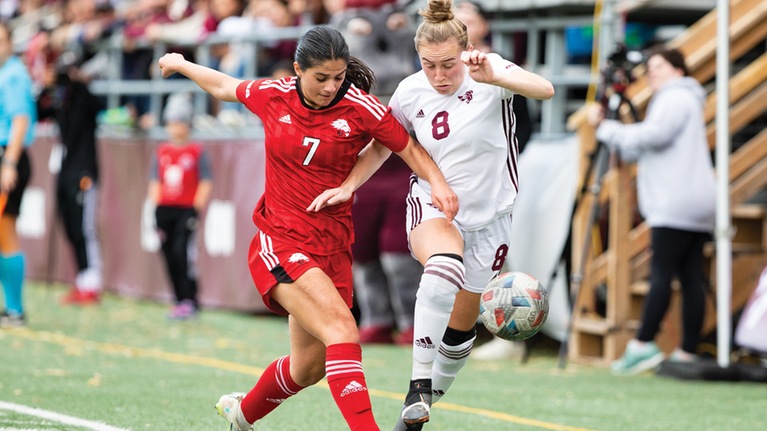 Ottawa and York women's soccer players converging for the ball on the field