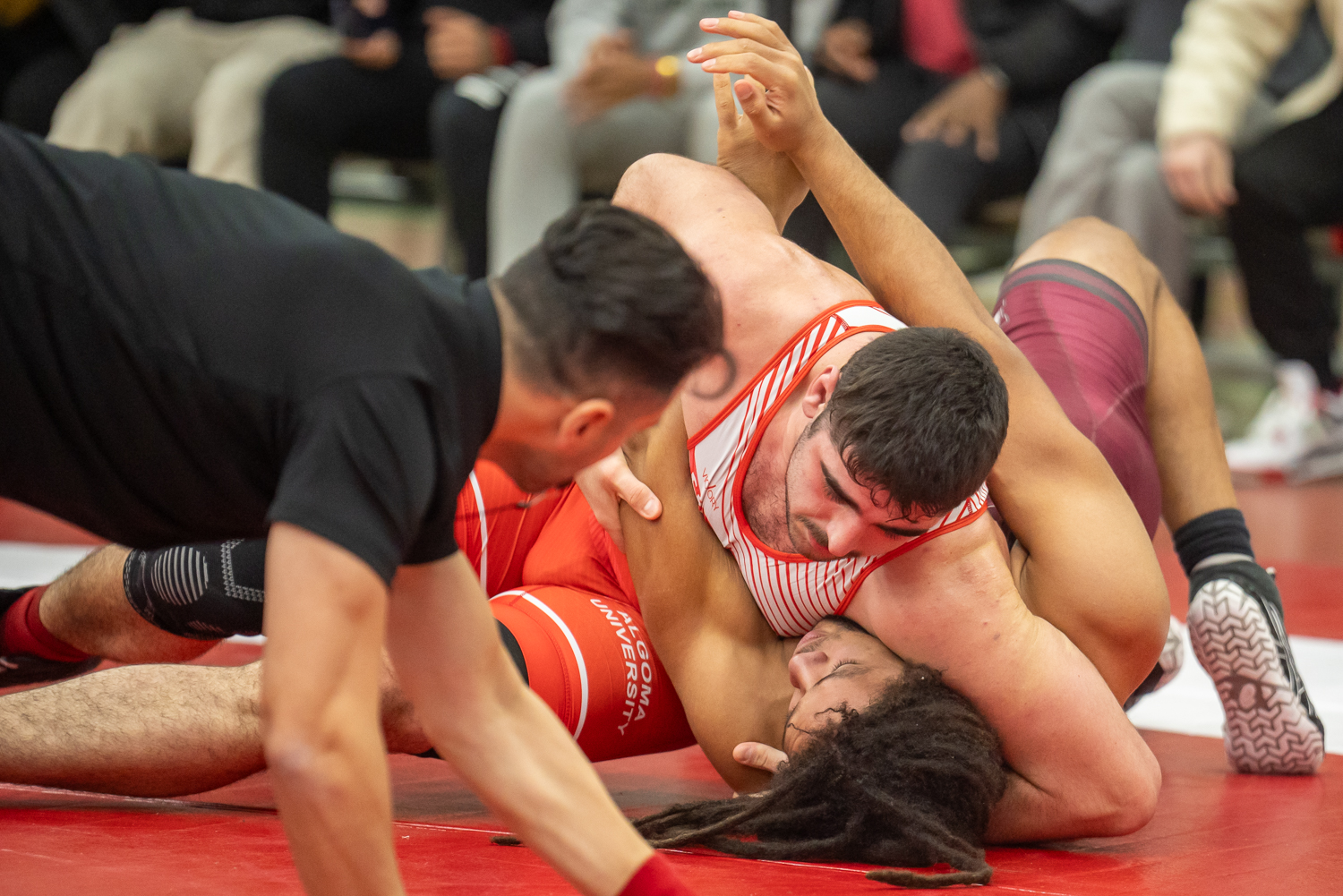 Image of Algoma Men's wrestler Kyle Price wrestling on the mat pinning someone down 