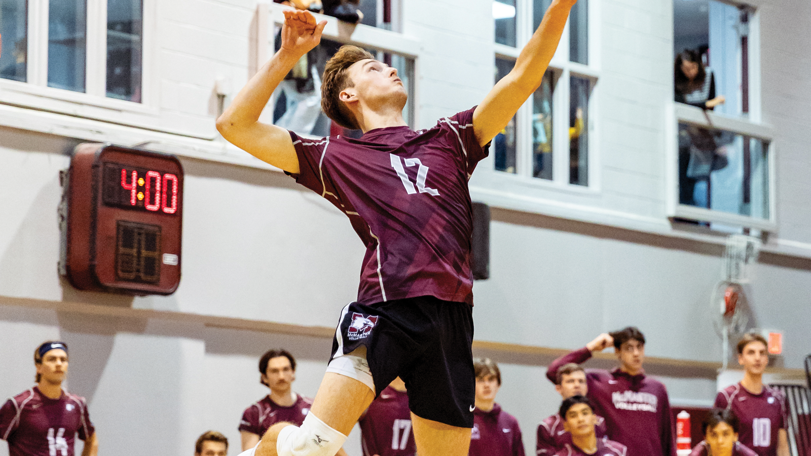 McMaster men's volleyball player Brady Paterson jumping in the air to serve the ball during a game